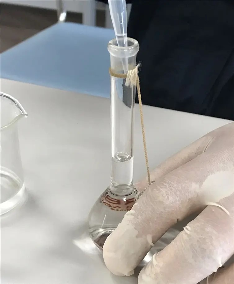 图5. 用玻璃棒或类似的东西引导溶液，将溶液从烧杯转移到25毫升的容量瓶中。